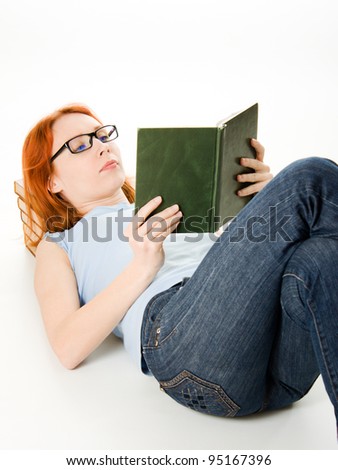 Young beautiful woman with red hair reading book laying on the floor.