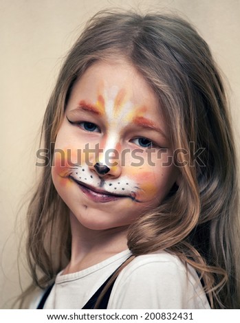 closeup portrait of little girl with cat painting makeup on the face looking at camera