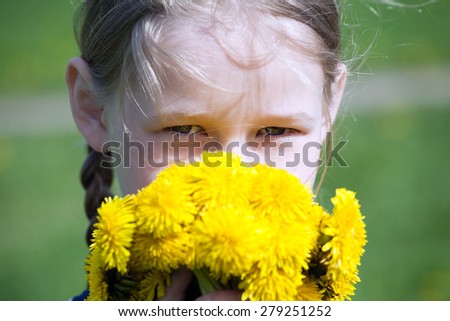 young pretty caucasian girl with yellow dandelions in hands, face closeup