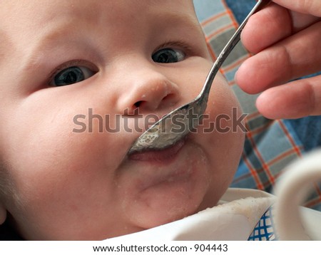 baby with a spoon in a mouth