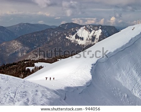 three persons walking down a mountain with ski in hands. Red Field, Caucasia, Russia