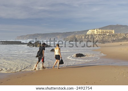 young man and woman walking along ocean