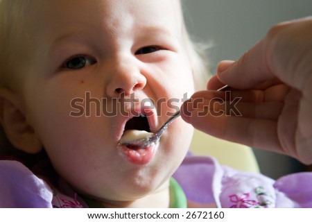 amusing baby with spoon of pap in a mouth