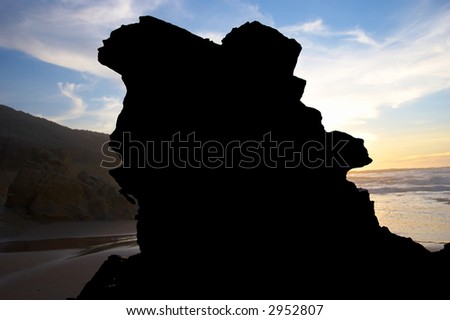 black silhouette of big rock on sunset sea background
