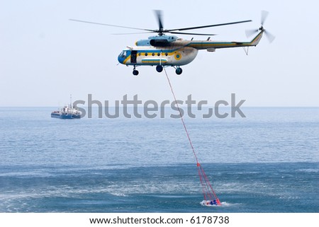 fire helicopter taking water from the sea to its special tank