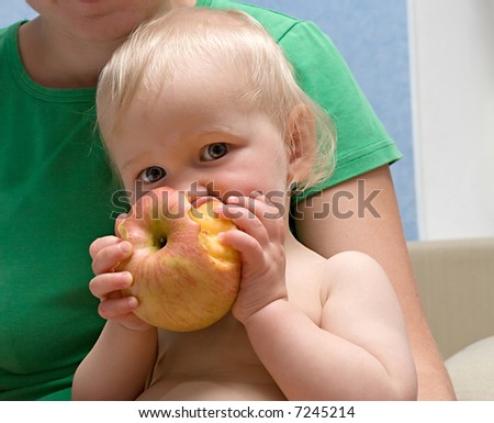 cute baby eats yellow apple. close-up portrait on black background