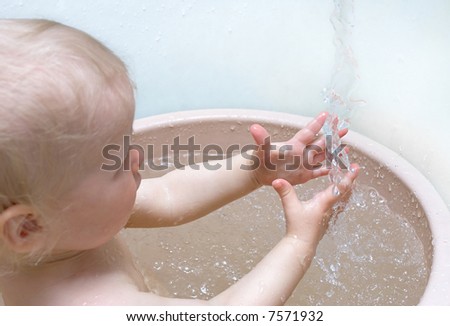 funny baby in bath playing with falling water