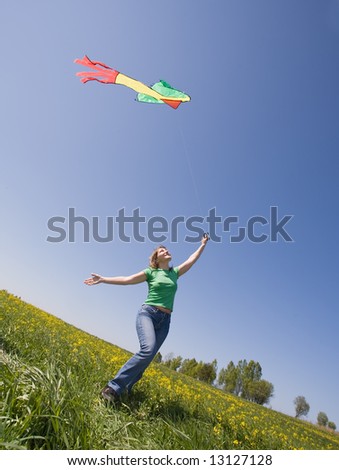 young woman flying kite on a green meadow