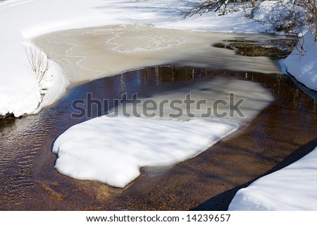small spring stream with snow banks at sunny day