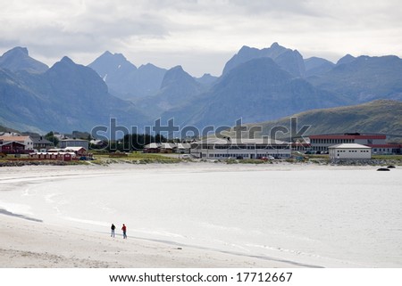 man and woman walking on the sandy beach in northern Norway coast of Arctic ocean