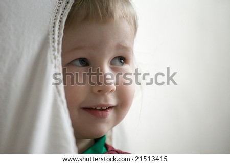 little girl with the opened look behind window curtain