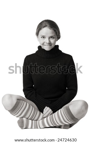 beautiful girl in sweater and long striped socks sits on floor crossed legs in funny yogi pose