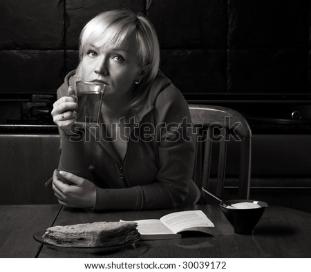 beautiful thoughtful girl sits in a cafe with cup of tea and  a book on the table