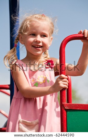 portrait of 5 years old blonde girl in summer pink dress on playground