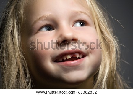 portrait of a funny little girl without one front tooth