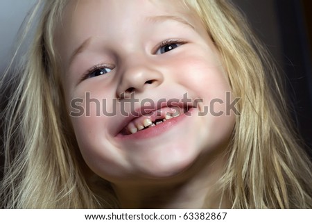 closeup portrait of funny smiling little girl without one front tooth