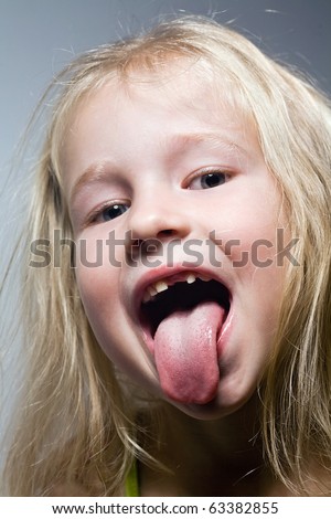 closeup portrait of funny smiling little girl with tongue out and without one front tooth