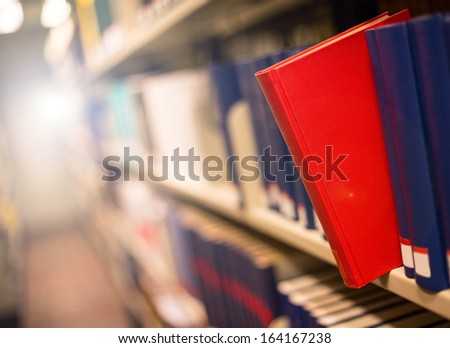 plain book jut out a bookshelf with light in the back