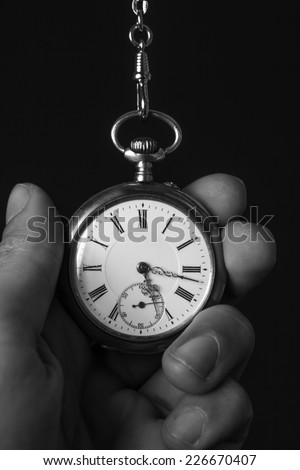 old pocket watch in black and white in human hand