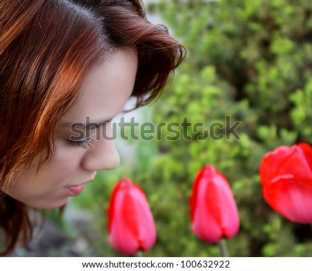 beautiful redhead smelling tulips in a garden
