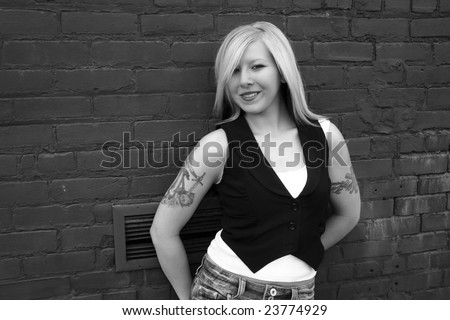 Bleach blonde with tattoos against a wall