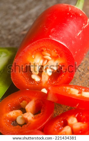 red and green jalapeno peppers on a stone textured table