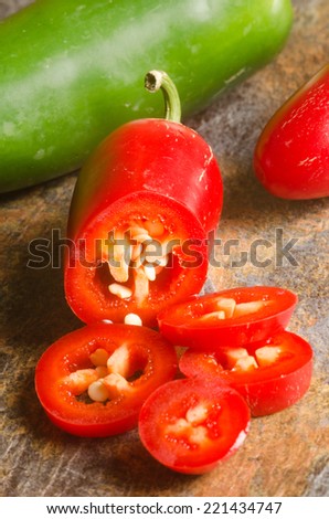 red and green jalapeno peppers on a stone textured table