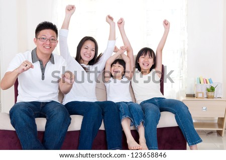 Asian family watching television and shouting on their home side in a sporting competition