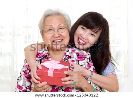 Asian senior woman receiving gift from daughter