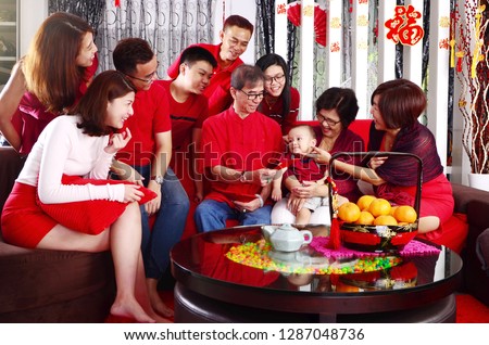 Asian three generations family celebrating chinese new year. Grandfather giving red packet to his youngest grandchild. Chinese characters in the photo means 