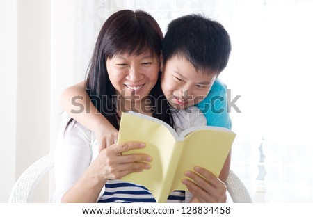 Asian woman and her son sharing a book