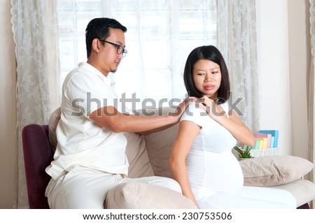 Asian man massage for pregnant wife who is suffer from shoulder pain
