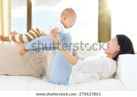 Asian mother lifting up her baby with legs