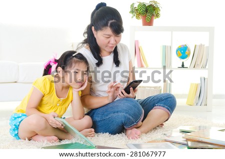 Asian child frustrated with her mother who is busy playing handphone