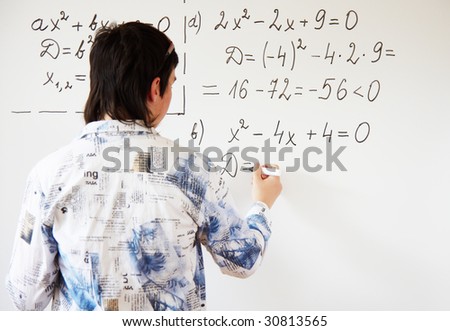 Young teacher teaching algerbra  and writes quadratic equation on a whiteboard