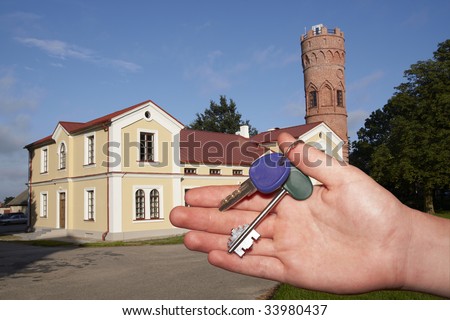 New house owner. Key in hand and new cottage on background.