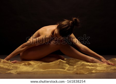 Naked woman on black background. Fine art photo of female body.
