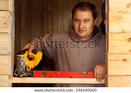 young man carpenter builder working with electric fret saw and wood