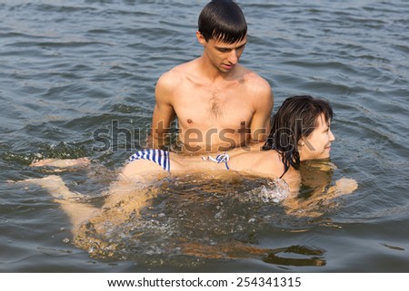 young multiethnic couple has fun in the sea, learns to swimming