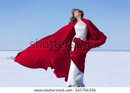 Woman in white bride dress with flying red fabric. Winter background