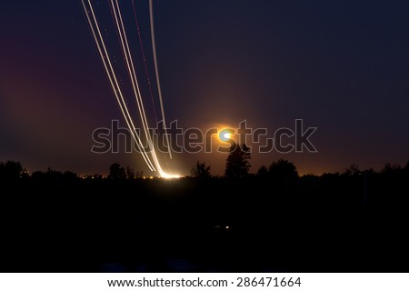 Passenger planes take off from runways against beautiful night sky with moon. Long exposure. Motion blur, and light trace