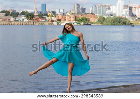 Attractive girl have fun at the urban beach in the water. Woman portrait with blue dress.