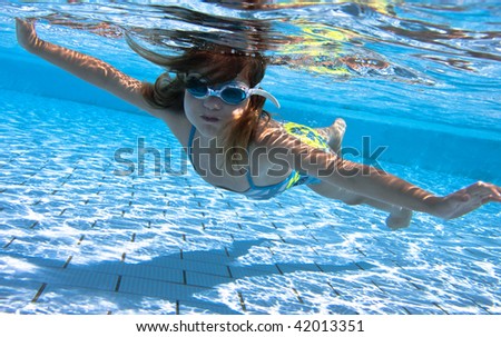 small girl swimming under water in the swimming pool