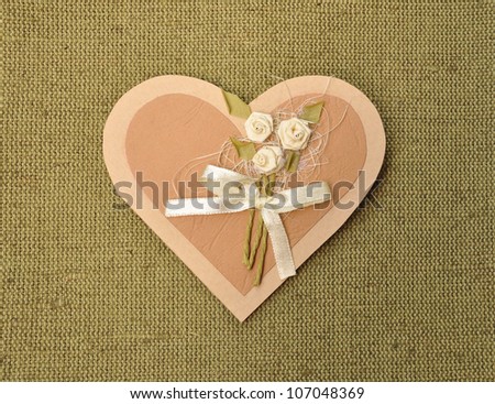Handmade paper gift or invitaion card love heart shape decorated with flowers on canvas background.