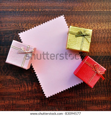 Empty pink paper gift card with gift box top view on table abstract background