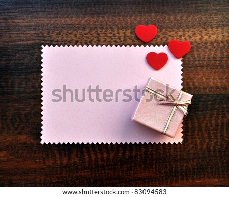 Empty pink paper gift card with love hearts and gift box with bow on table