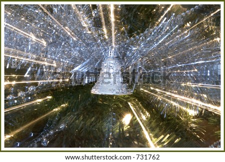 Streaks of silver garland and white lights on a christmas tree with focus on silver bell.