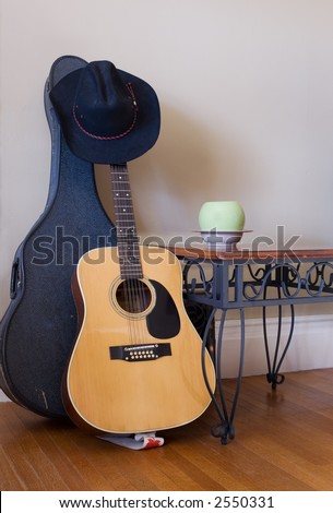 Wrought iron table, modern planter, old wood floors and textured walls with guitar and guitar case.