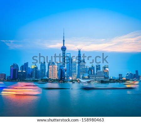 beautiful shanghai skyline with motion blur river boats in nightfall