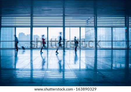 commuters motion blurred with modern corridor in high speed rail station